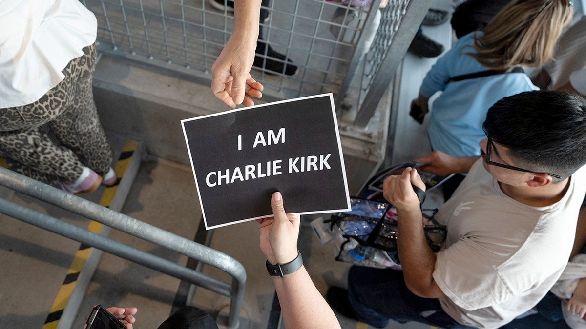 Charlie Kirk supporters passing a sign at a vigil at Colorado State University in Fort Collins