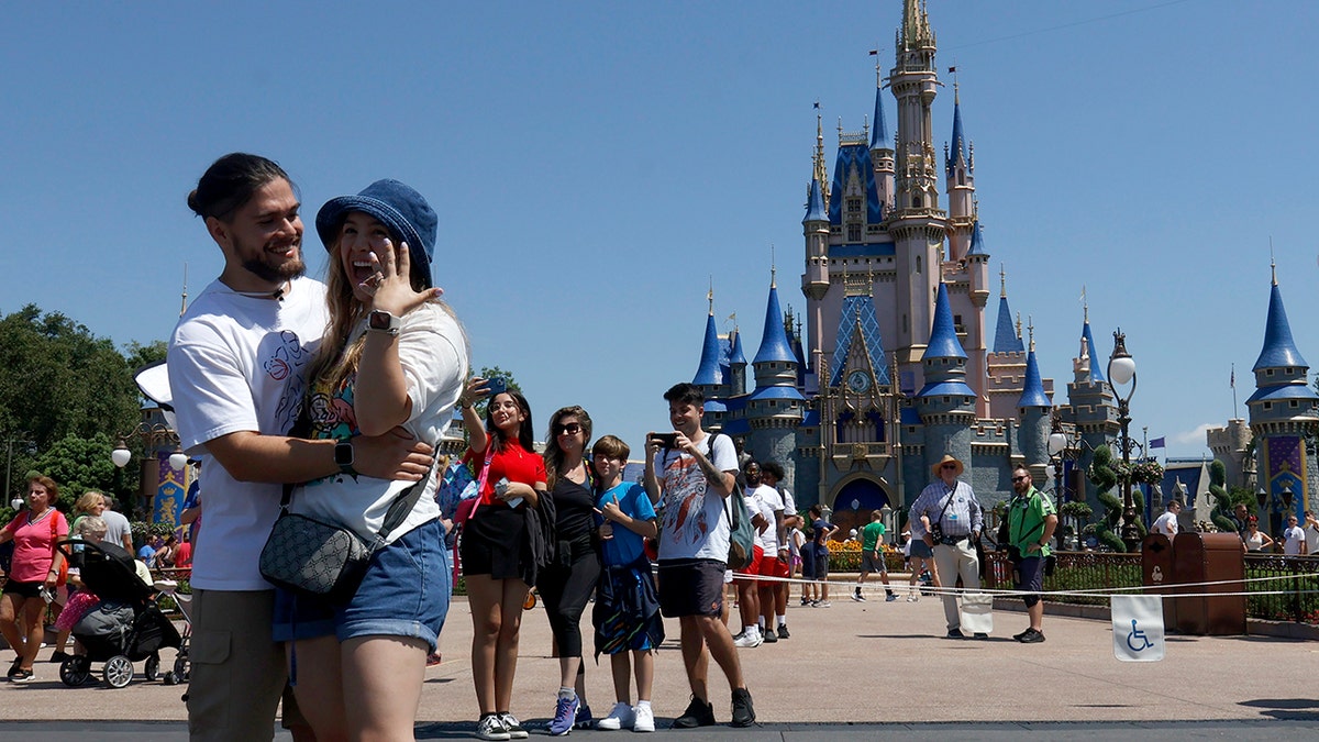 Couple poses with woman showing off her ring after getting engaged at Disney World