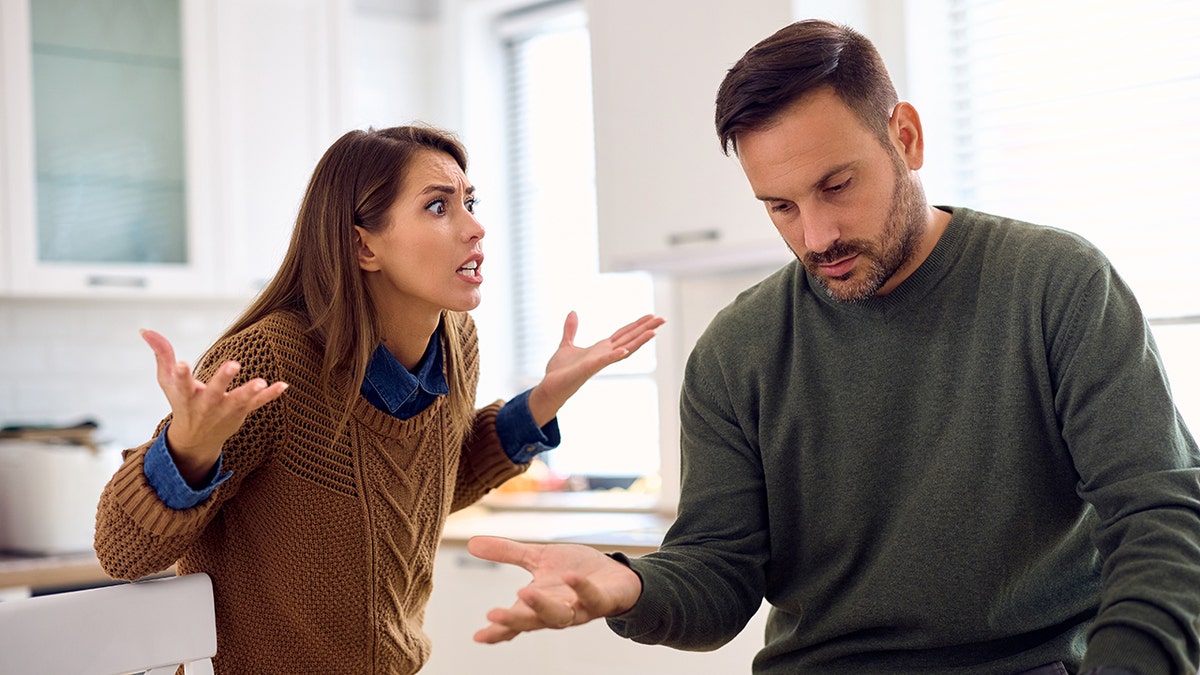 Woman seen yelling at husband, looking frustrated, as he looks down, also looking upset