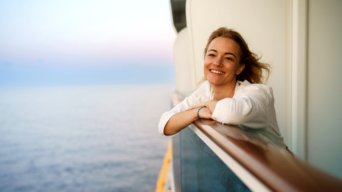 A woman smiling on a balcony of a tourist ship