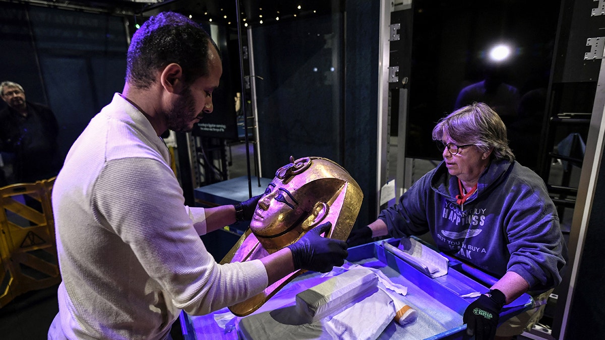 Curators examining mask of Pharaoh Amenemope