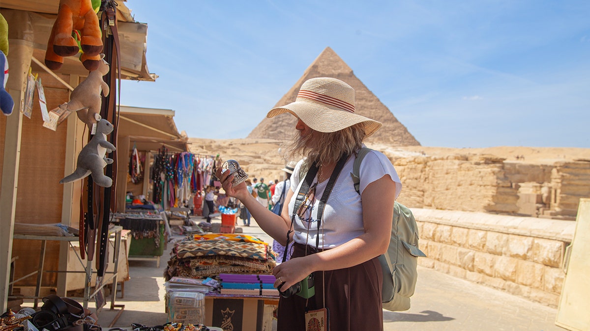 Tourist inspecting item at egyptian merchant stall