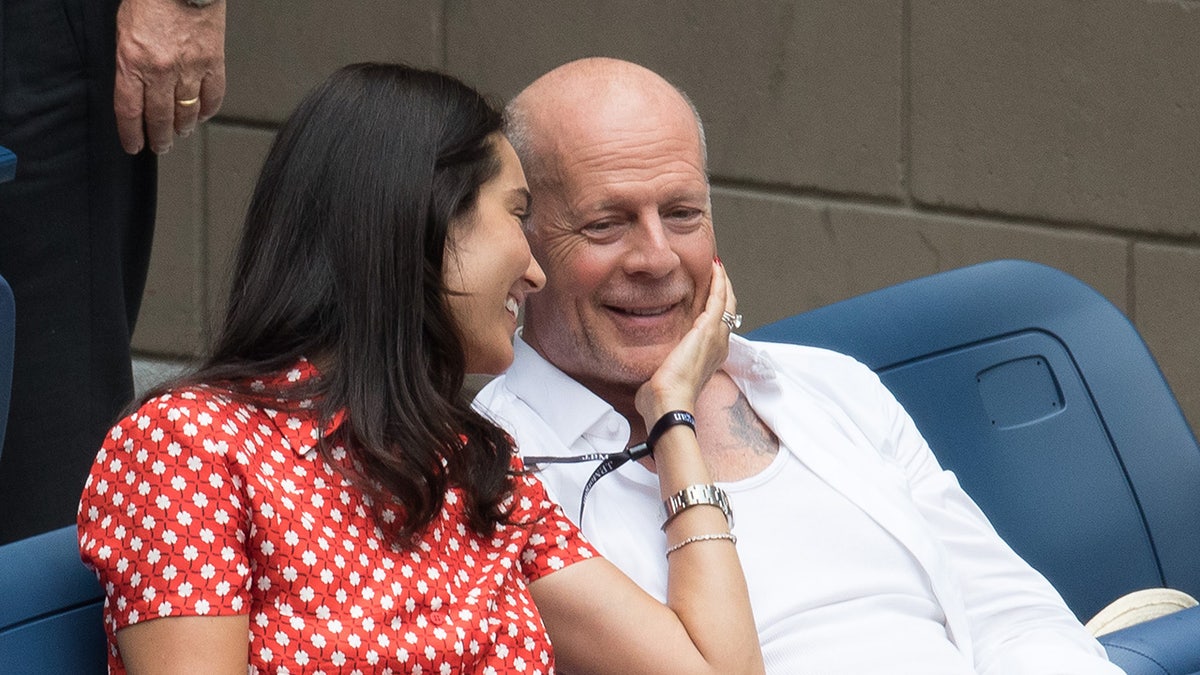 Emma Heming Willis holding Bruce Willis's chin as he smiles.