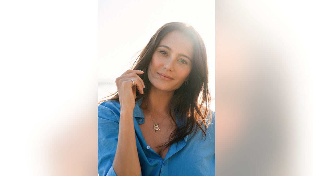 Emma Heming Willis wearing a blue shirt and posing near sunlight.