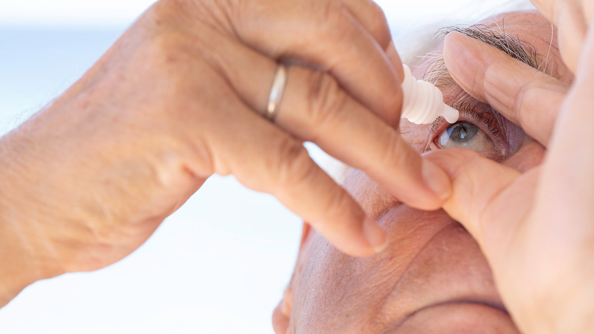 Man applying eye drops very close up