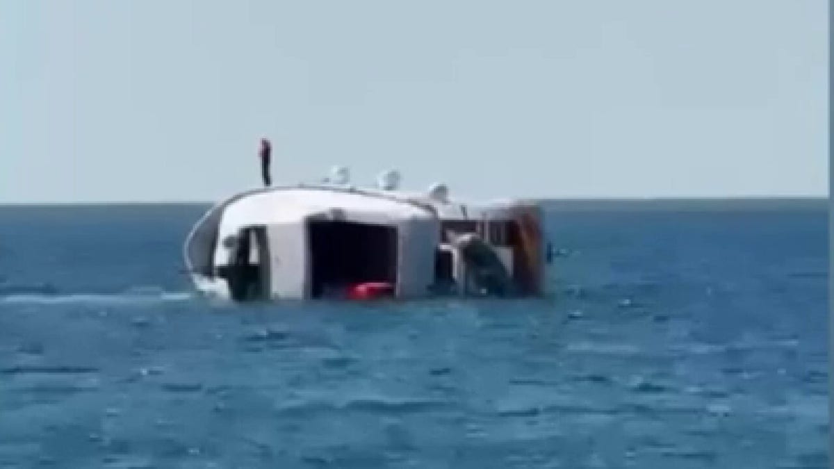 Man standing on side of sinking yacht
