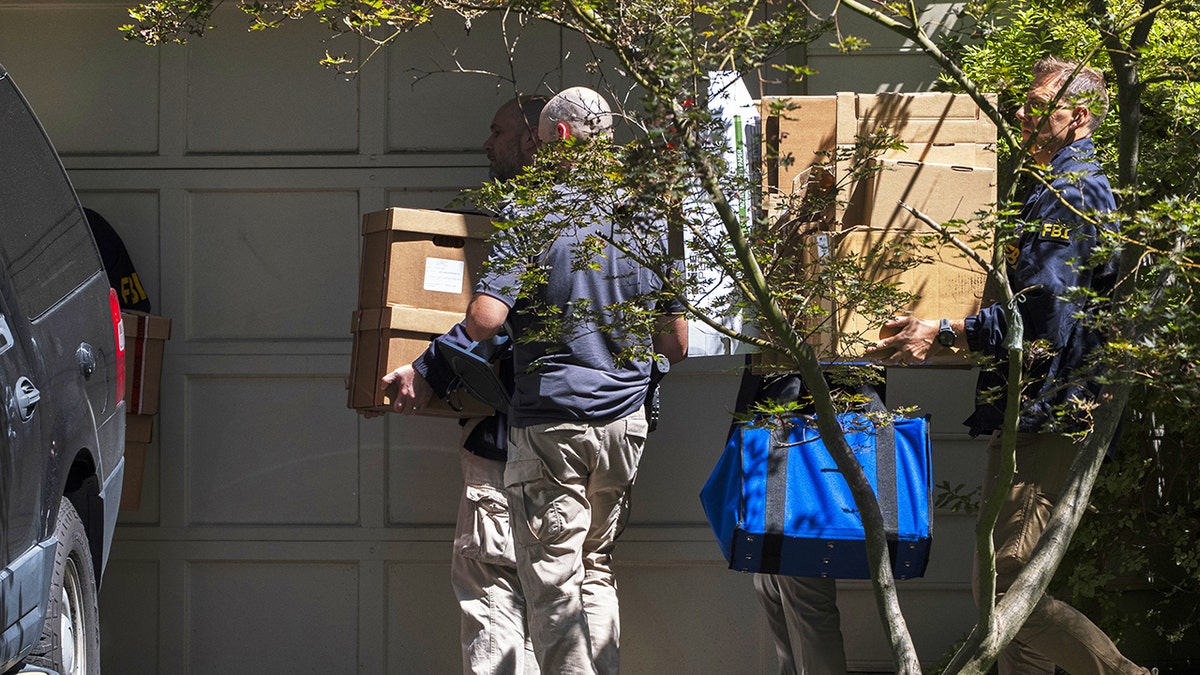 FBI agents carrying boxes to cars outside Bolton's home