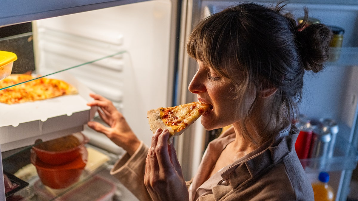 Woman eating pizza late at night