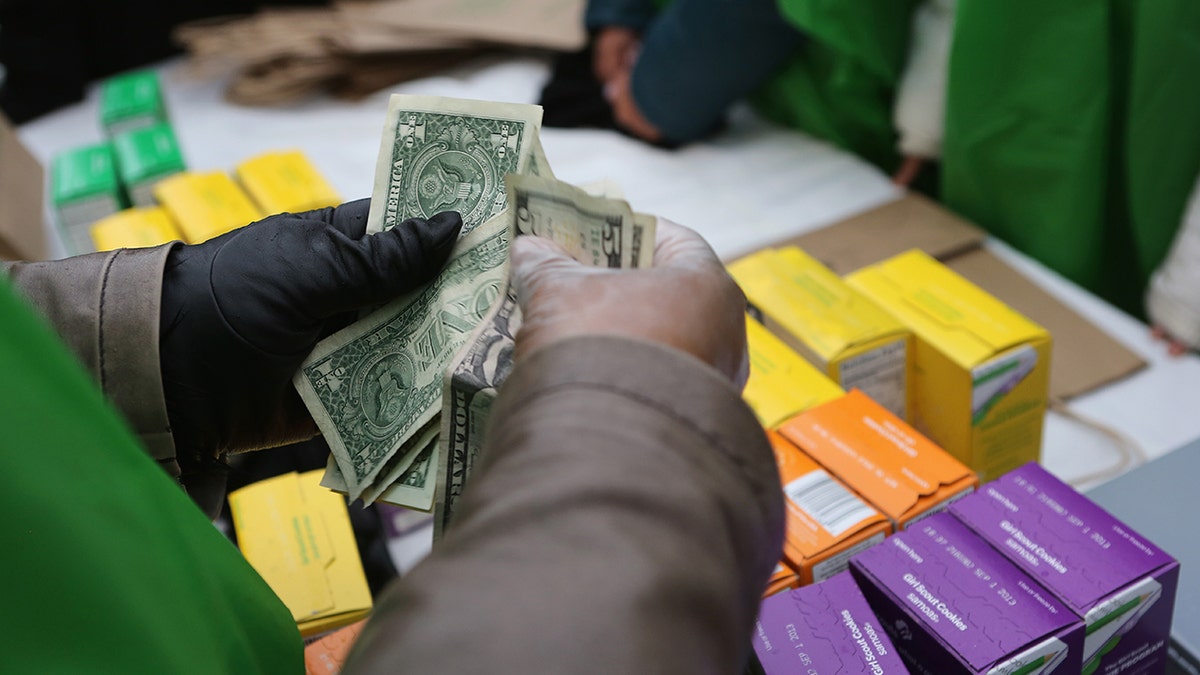 Persons' hands counting money as they buy girl scout cookies, as Girl Scouts announces new rocky road–inspired cookie debuting in 2026 with chocolate, marshmallow and toasted almond crème filling. 