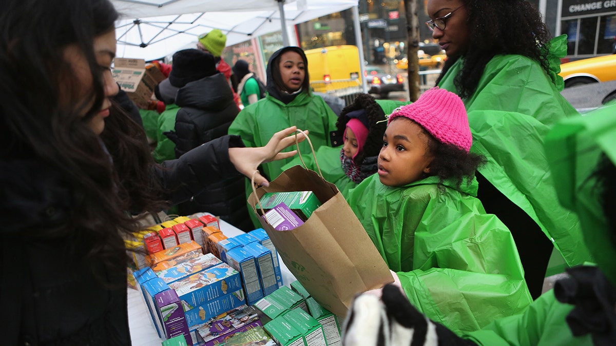 Girl scouts in ponchos sell cookies in Midtown Manhattan during winter storm in 2013.