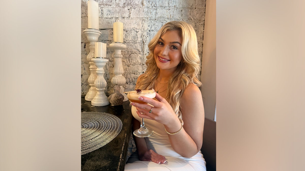 A young woman holds a martini in her hand.