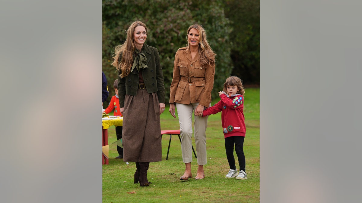 Kate Middleton and Melania Trump walking together with a child.