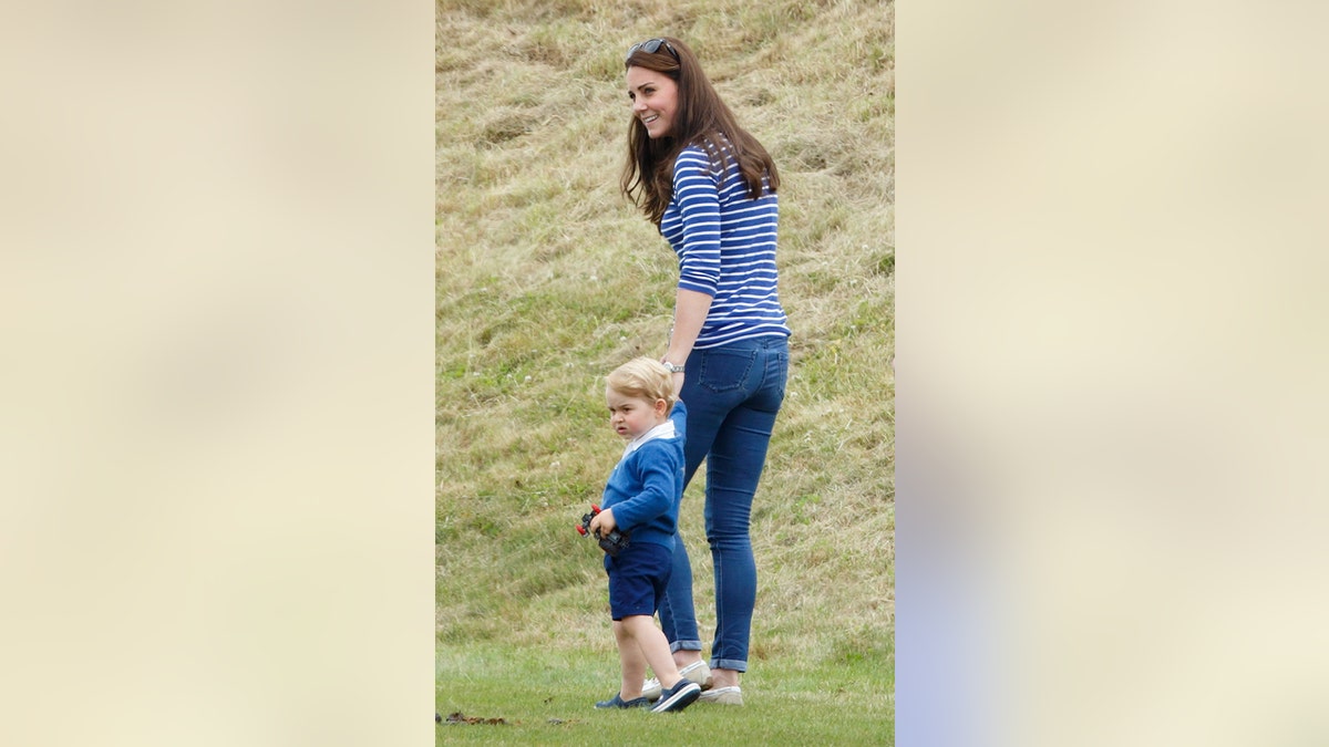 Kate Middleton in casual clothes walking in a friend with a young Prince George in blue shorts.