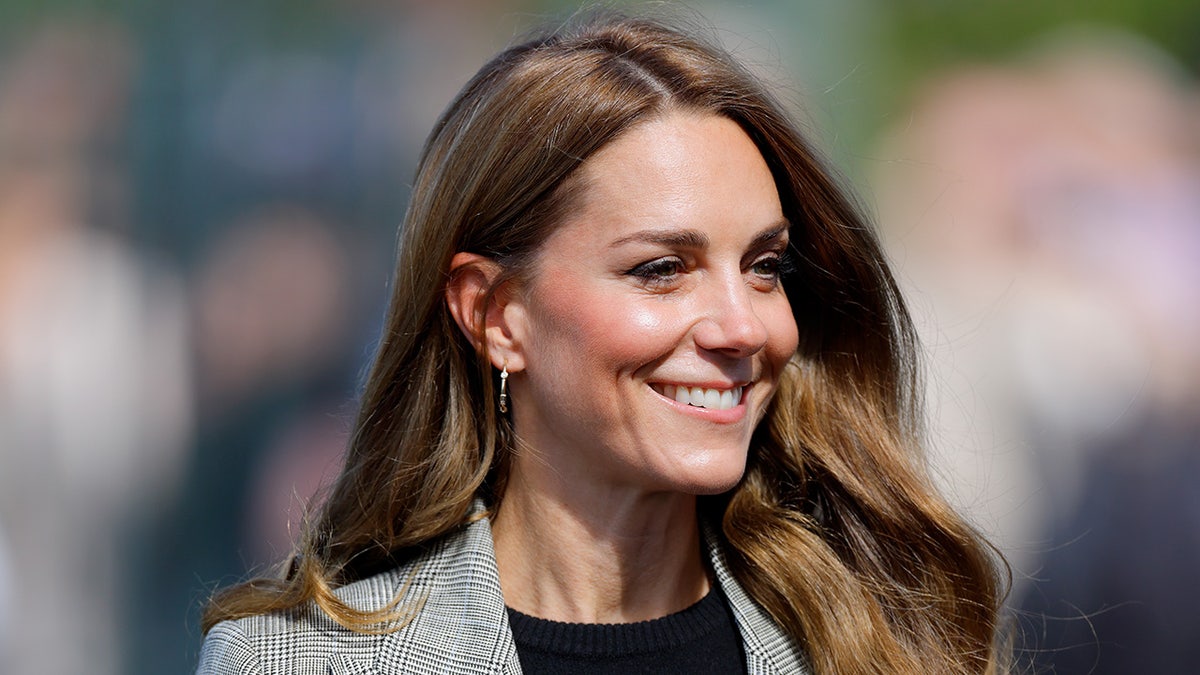 A close-up of Kate Middleton with "bronde" hair smiling at a royal engagement.