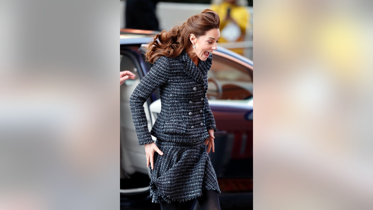 Kate Middleton looking surprise as her skirt begins to fly up.