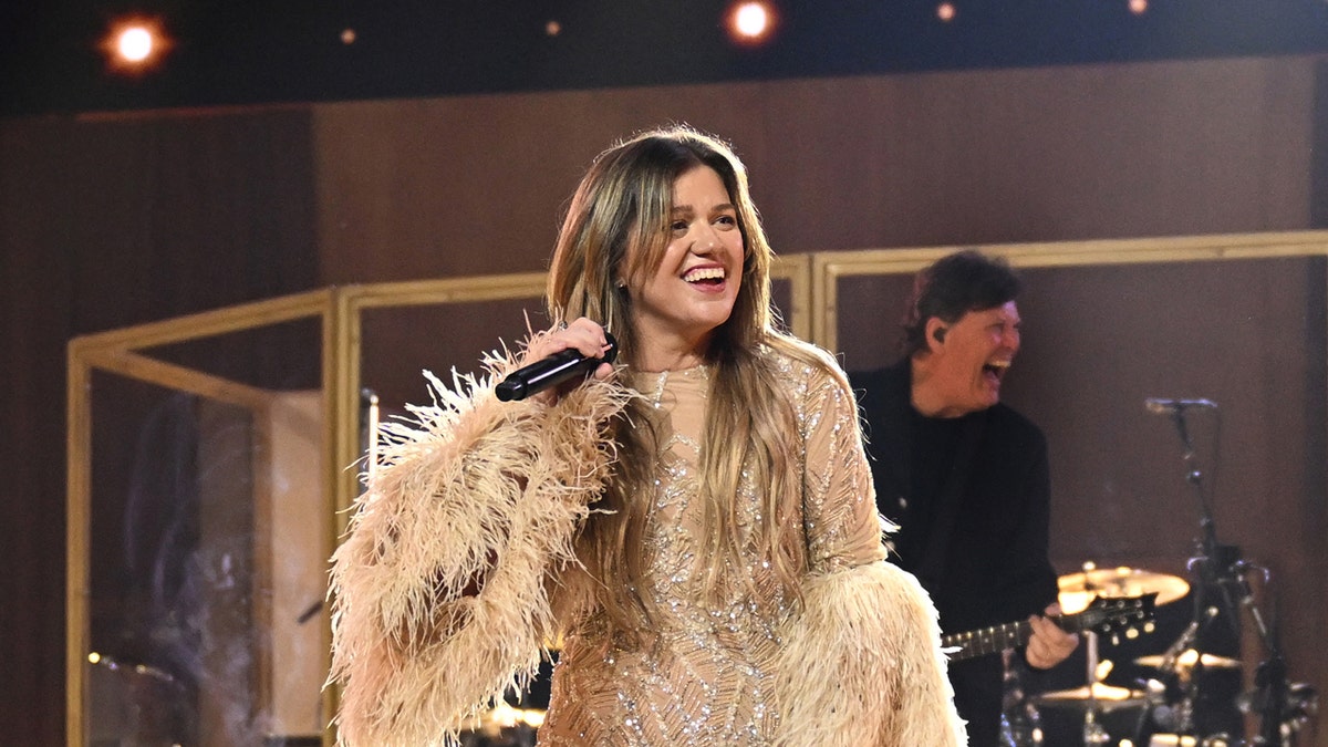 Kelly Clarkson performs on stage in a pink dress
