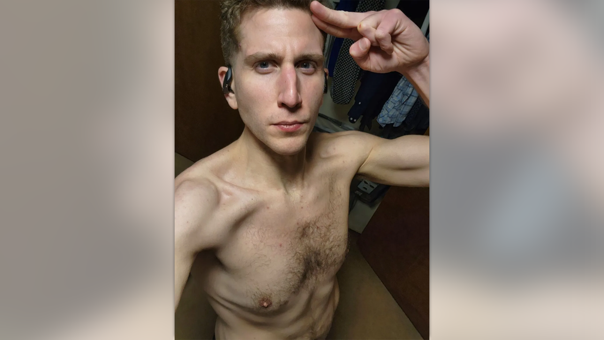 Shirtless Bryan Kohberger wearing wireless headphones, saluting the camera with a cut on his knuckle in a selfie