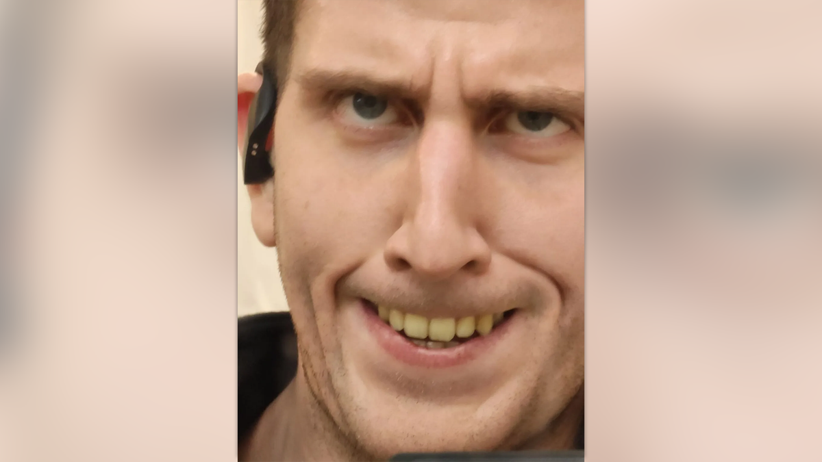 Kohberger makes a weird face, eyes looking upward, baring his yellow teeth, while wearing a wireless headphone