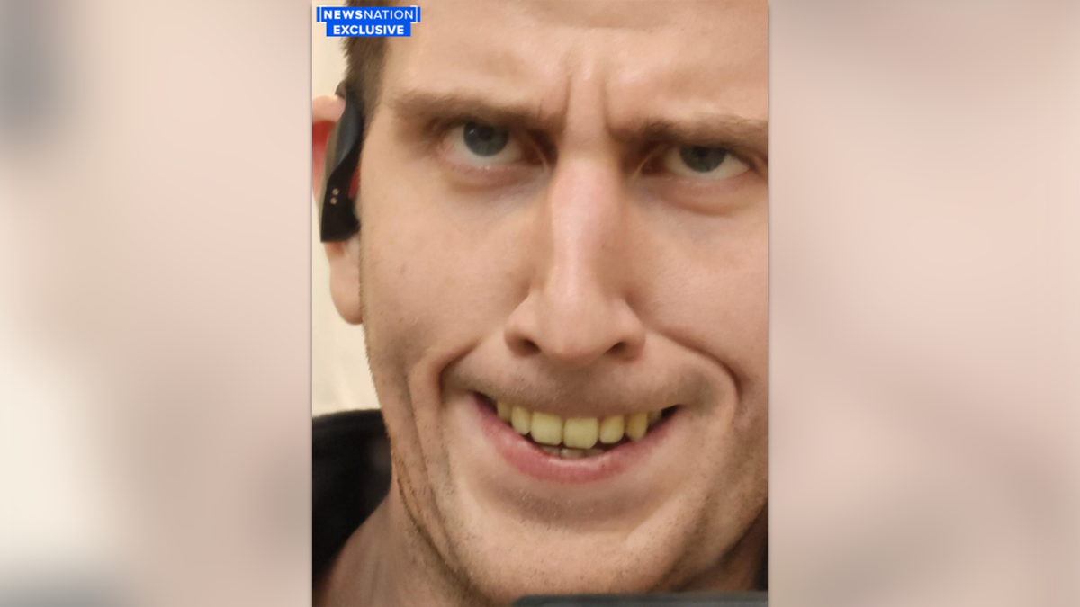 Kohberger makes a weird face, eyes looking upward, baring his yellow teeth, while wearing a wireless headphone