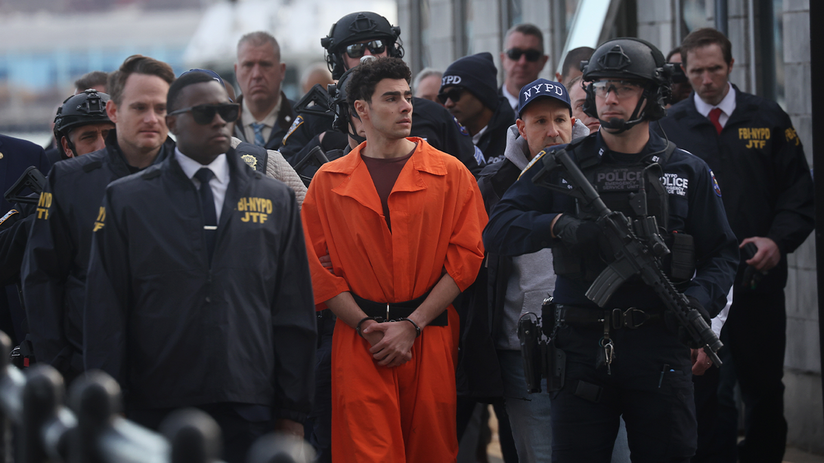 Luigi Mangione in an orange inmate jumpsuit, escorted by a large contingent from the NYPD and FBI's Joint Task Force