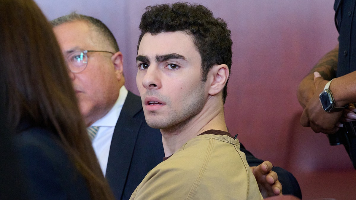 Luigi Mangione seated in court as judge drops terrorism charges.