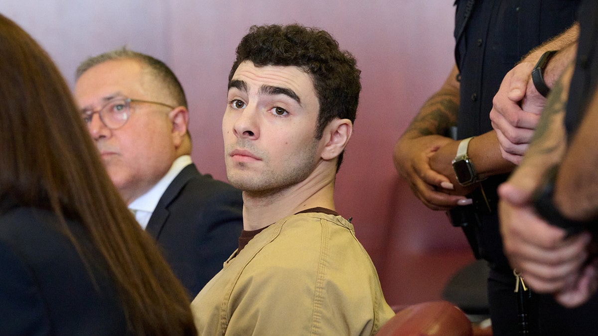 Luigi Mangione seated in court as judge drops terrorism charges.