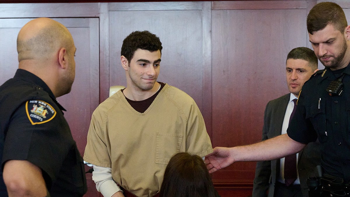 Luigi Mangione seated in court as judge drops terrorism charges.