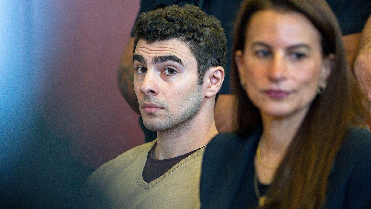 Luigi Mangione seated in court as judge drops terrorism charges.