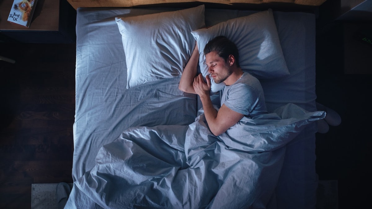 man sleeping in dark bedroom