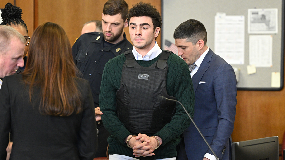 Luigi Mangione Attends Hearing In State Court In New York City wearing a protective vest on top of a green sweater