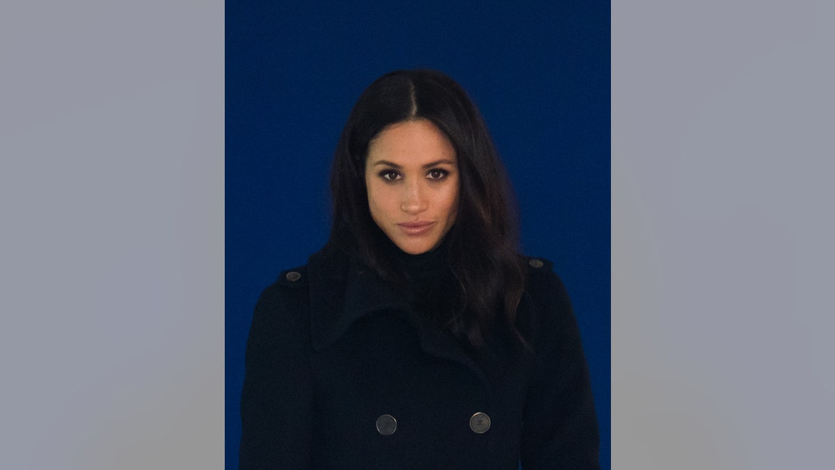 Meghan Markle looking serious wearing black.