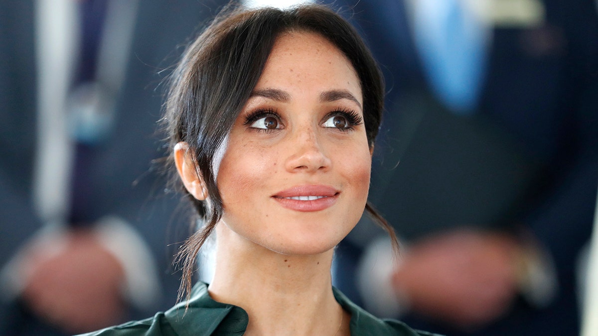 Meghan Markle looking up with a smirk.