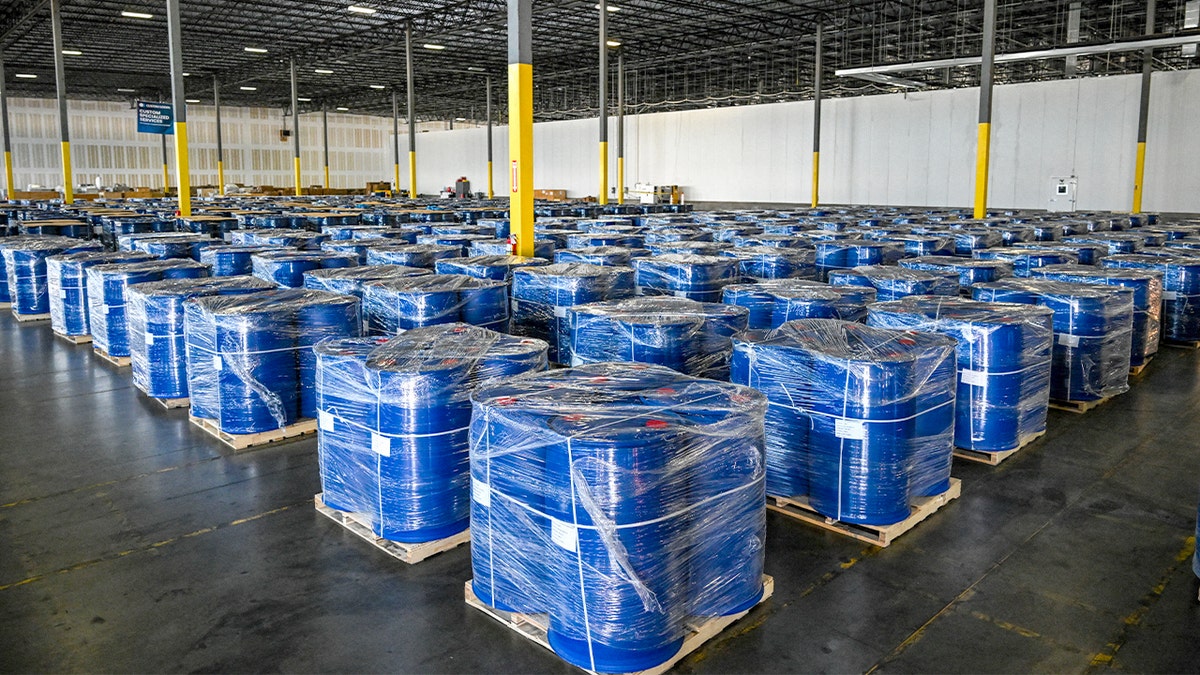 Large barrels filled with chemical substances displayed by law enforcement as evidence of a drug trafficking case.