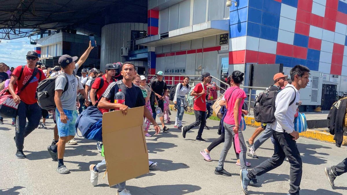 Migrants carrying bags and supplies walk across the border in Panama.