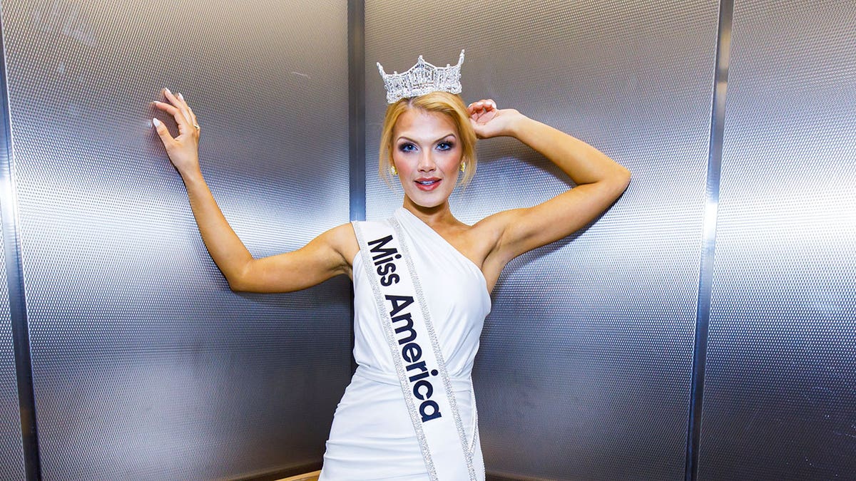 Miss America posing in her sash and white gown while wearing her tiara.