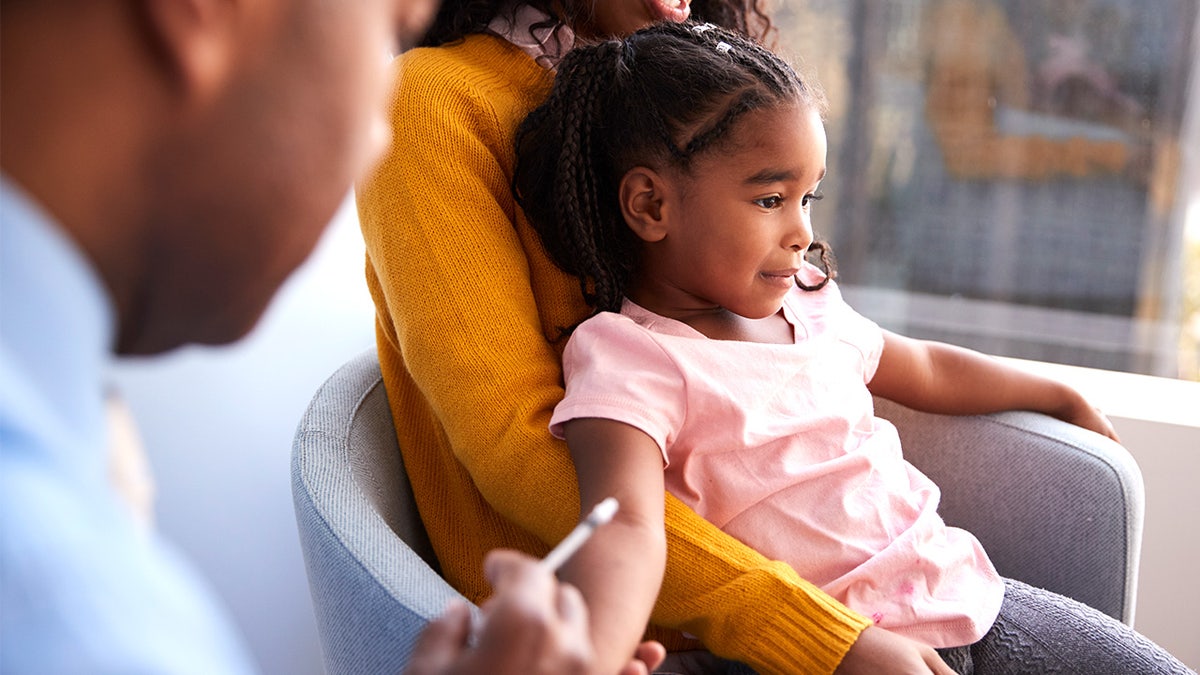 During a visit to the doctor’s office, the mother held the child while she was vaccinated.