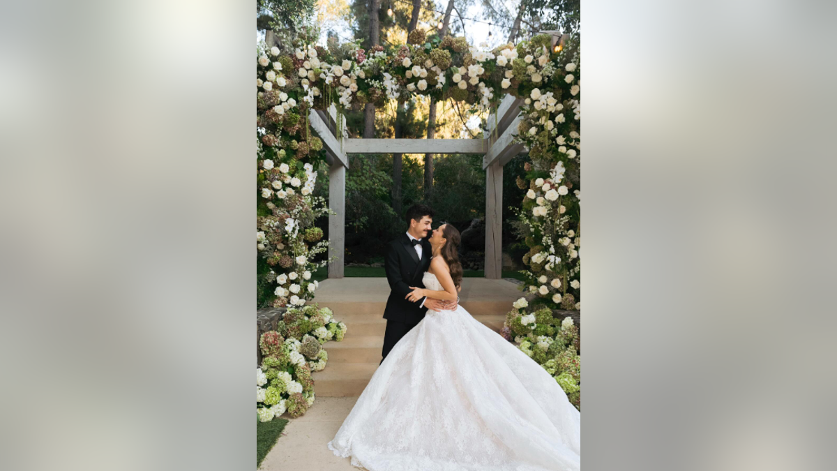 Natasha Bure and Bradley Steven Perry are pictured kissing at their wedding. 