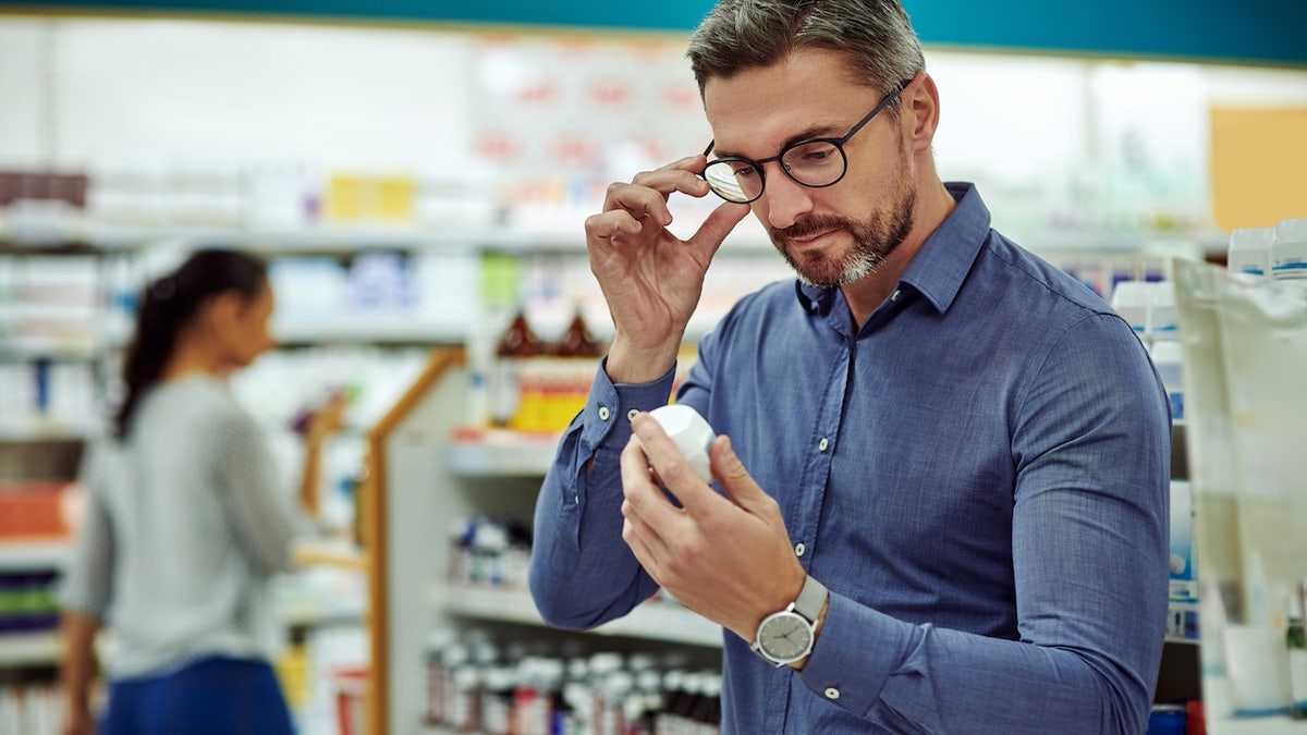 Older man looking at pill bottle