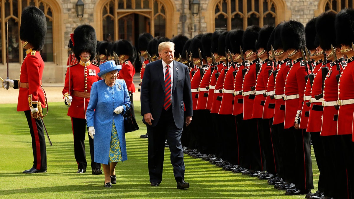 President Trump walking next to Queen Elizabeth II watching the guards.