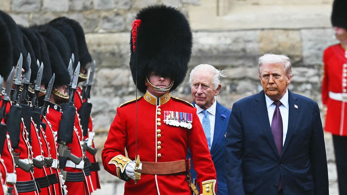 Donald Trump and King Charles walking together next to a royal guard.