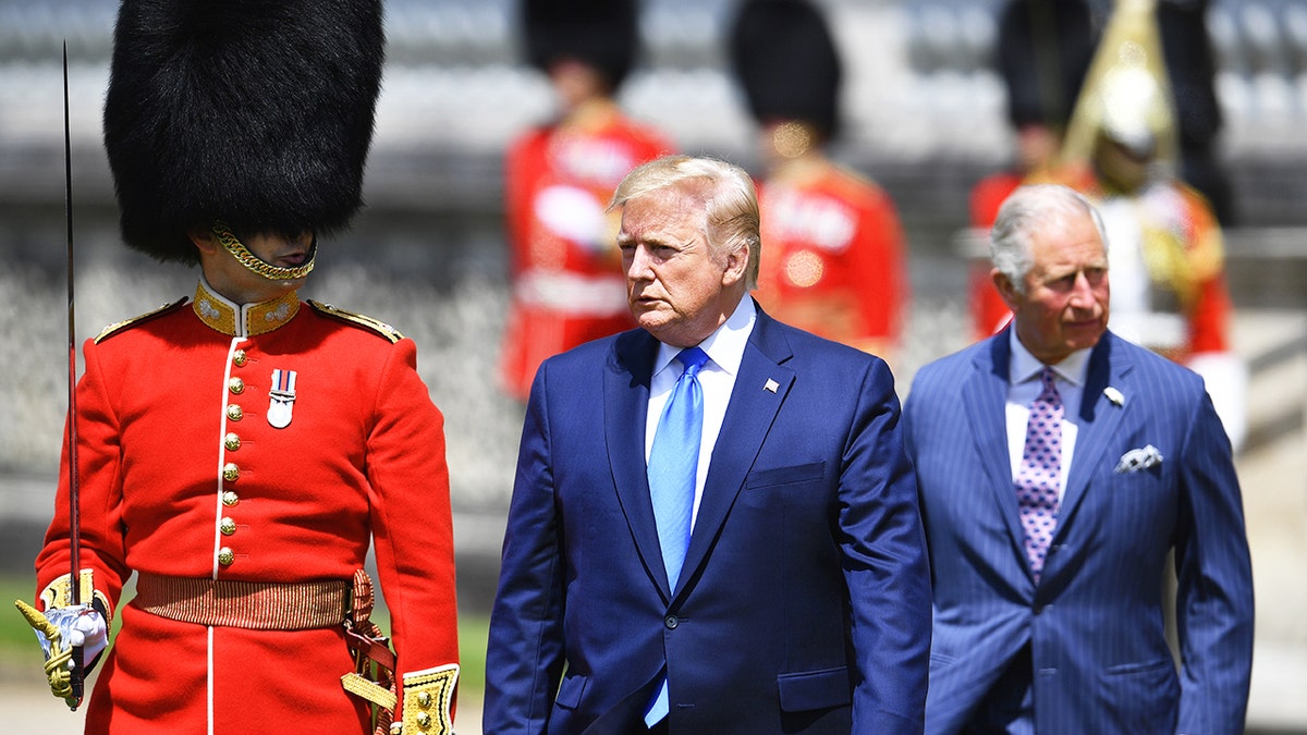 President Trump walks between the royal guards and King Charles.