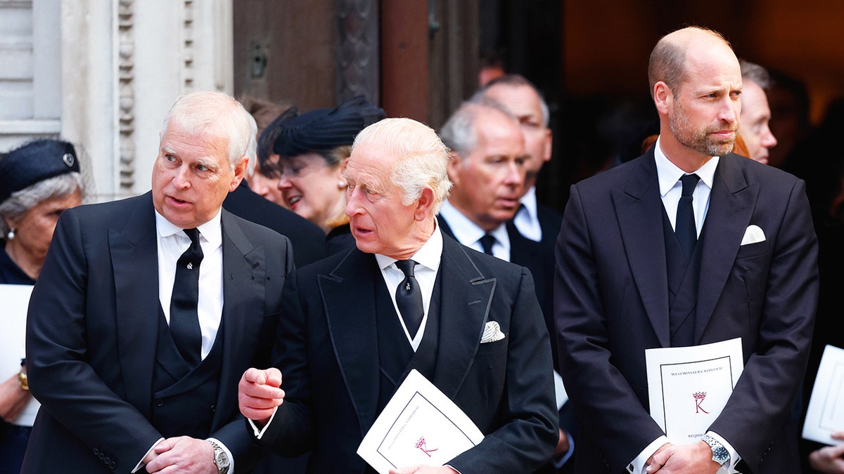 Prince Andrew, King Charles and Prince William standing in a line outside a church in dark suits.