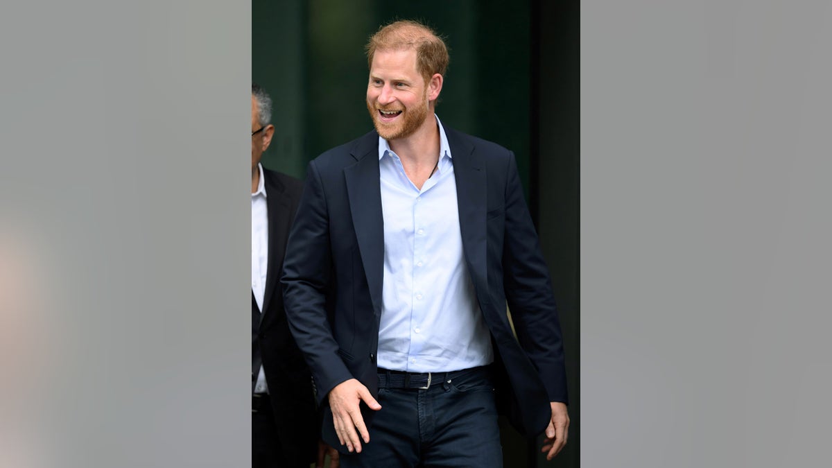 Prince Harry smiling and dress casually walking in London ahead of royal reunion.