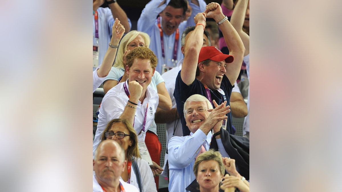 Prince Harry and Sir John Major cheering during a game.