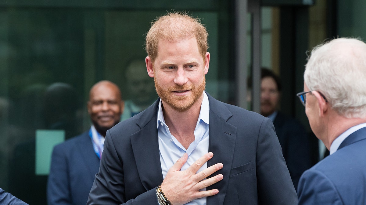Prince Harry with his hand to his chest as he talks to an older man in the U.K.