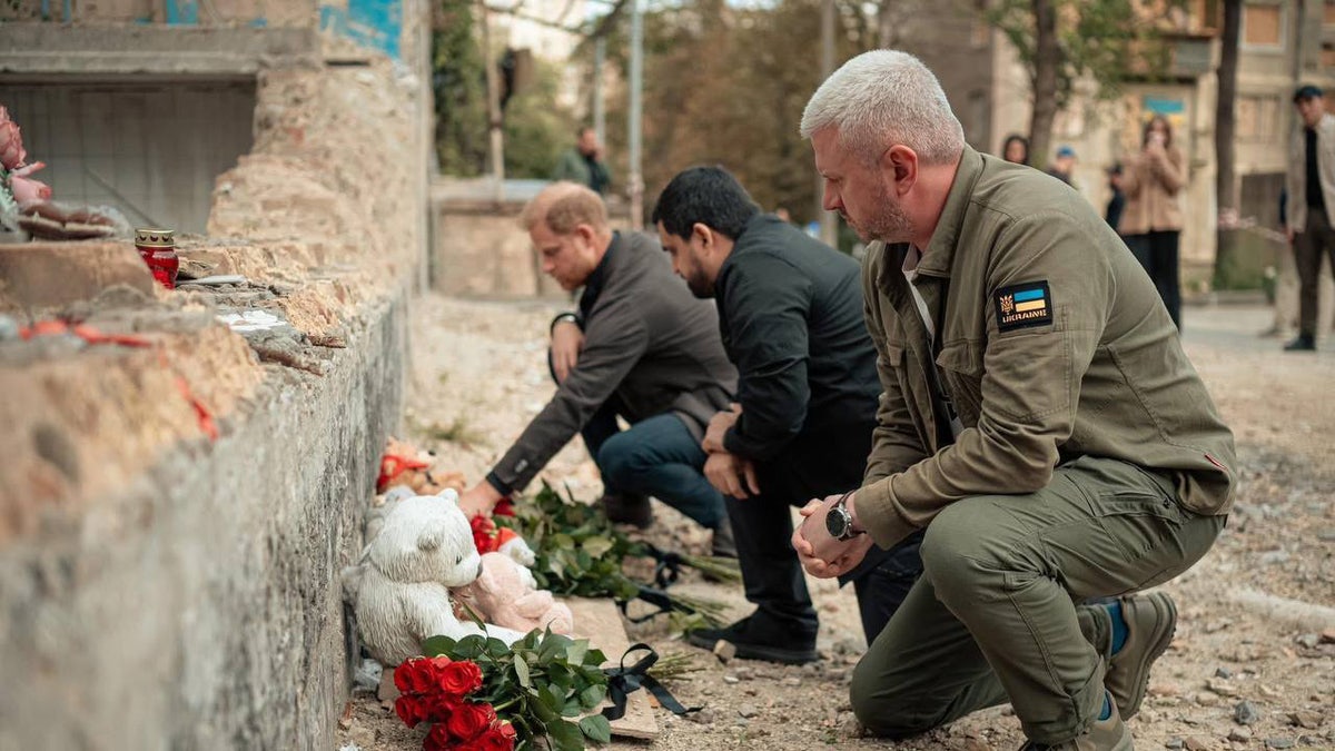 Prince Harry kneeling down and leaving flowers in Ukraine.