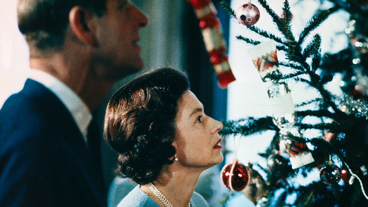 Prince Philip and Queen Elizabeth looking up at a Christmas tree.