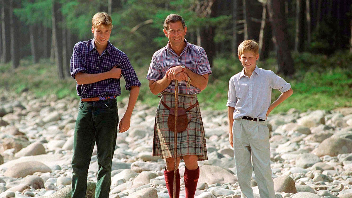 Prince William, King Charles and Prince Harry outdoors smiling for a portrait.