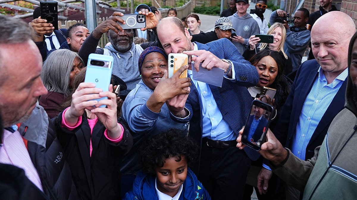 Prince William taking a selfie with a group of people.