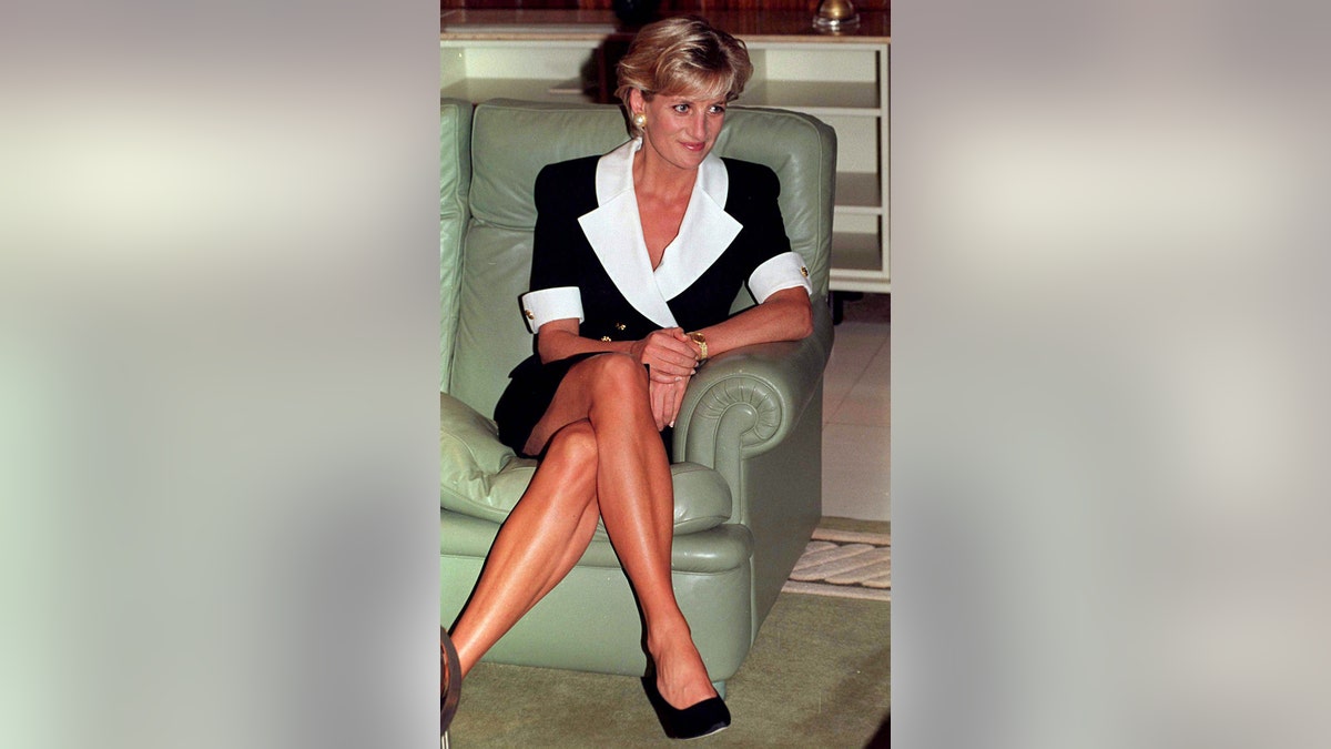 Princess Diana sitting on a green sofa showing off her tanned legs.